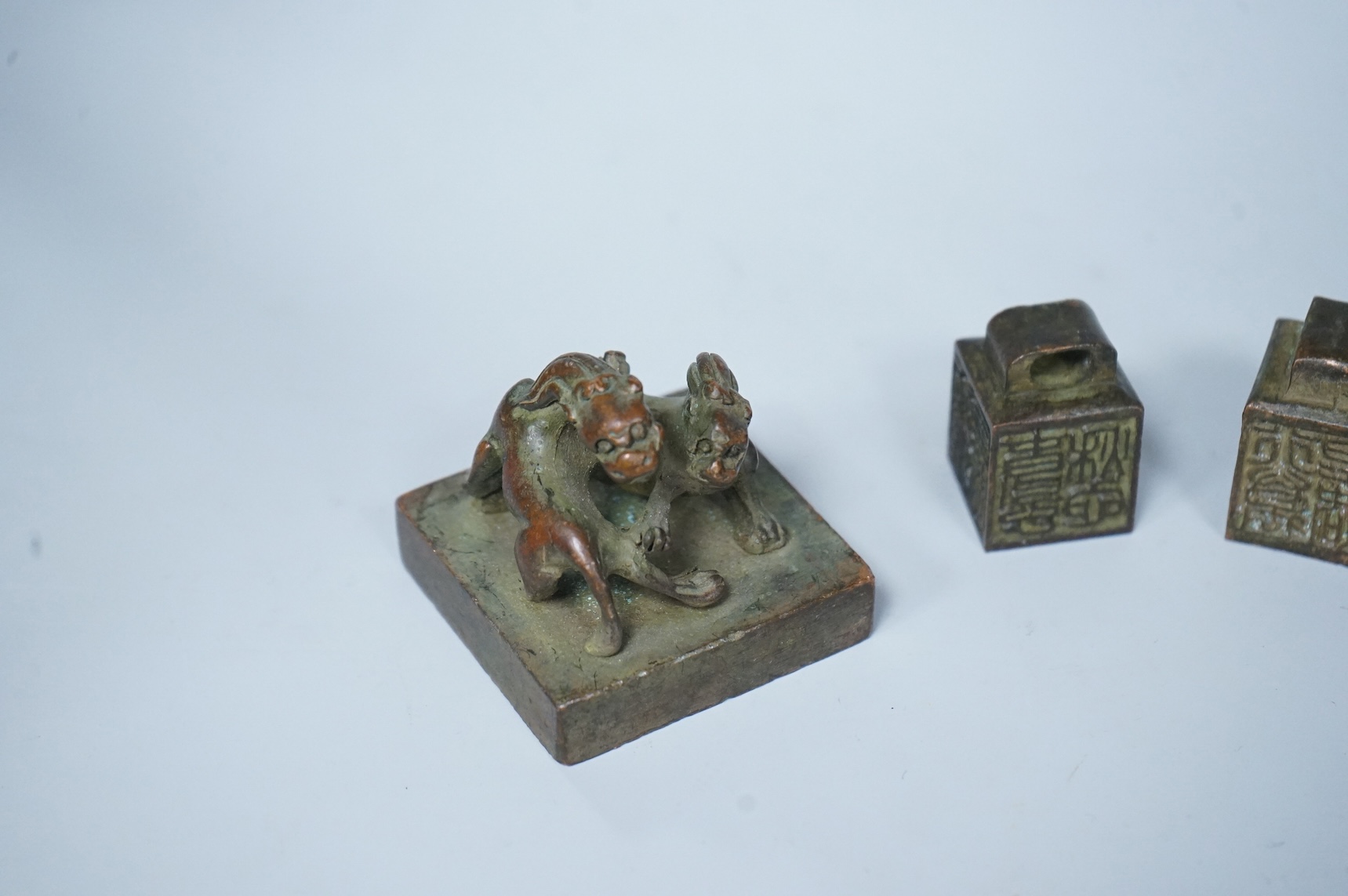 Four Chinese bronze seals, one in the form of two lion dogs, largest 7.5cm wide